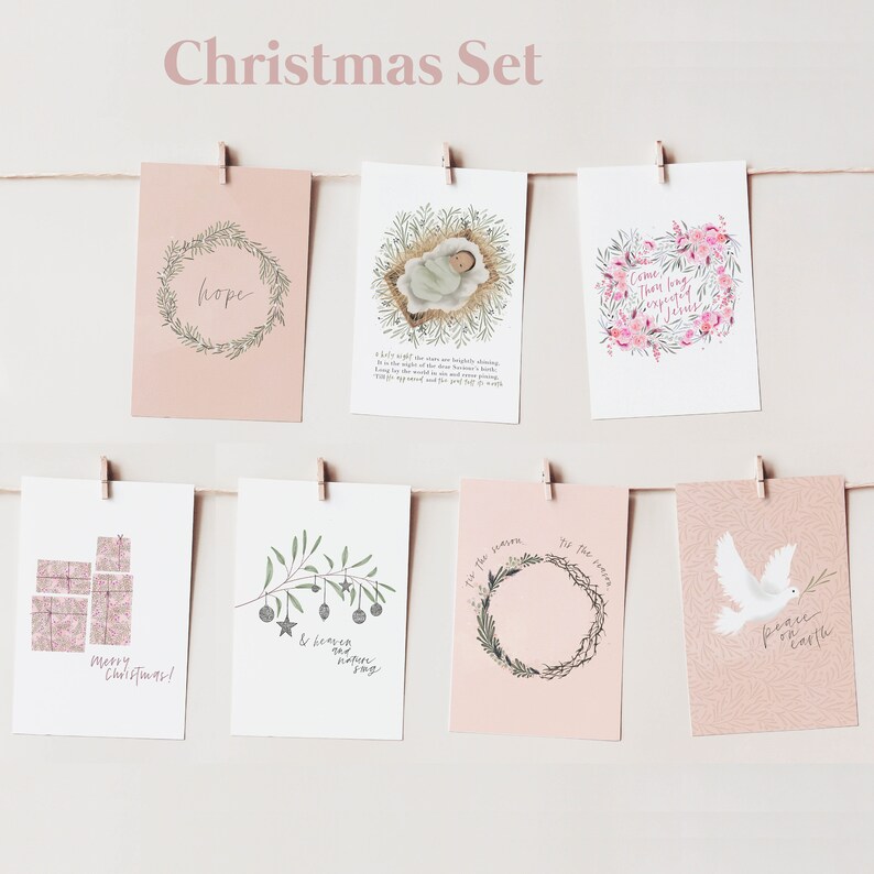 May include: Set of 8 Christmas cards with pink backgrounds and various illustrations. The cards feature wreaths, a baby in a manger, a dove, presents, and olive branches with ornaments. The text on the cards includes "Hope", "Come, there is a reason to believe in Jesus", "Merry Christmas", "& peace & never say", "Tis the season", "Peace on earth", and "I felt the star are brightly shining".
