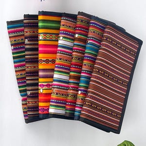 May include: A set of eight colorful striped wallets with black trim. The wallets are made of woven fabric with geometric patterns.