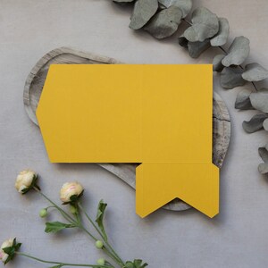 May include: A yellow paper box with a unique geometric design. The box is folded flat and ready to be assembled.