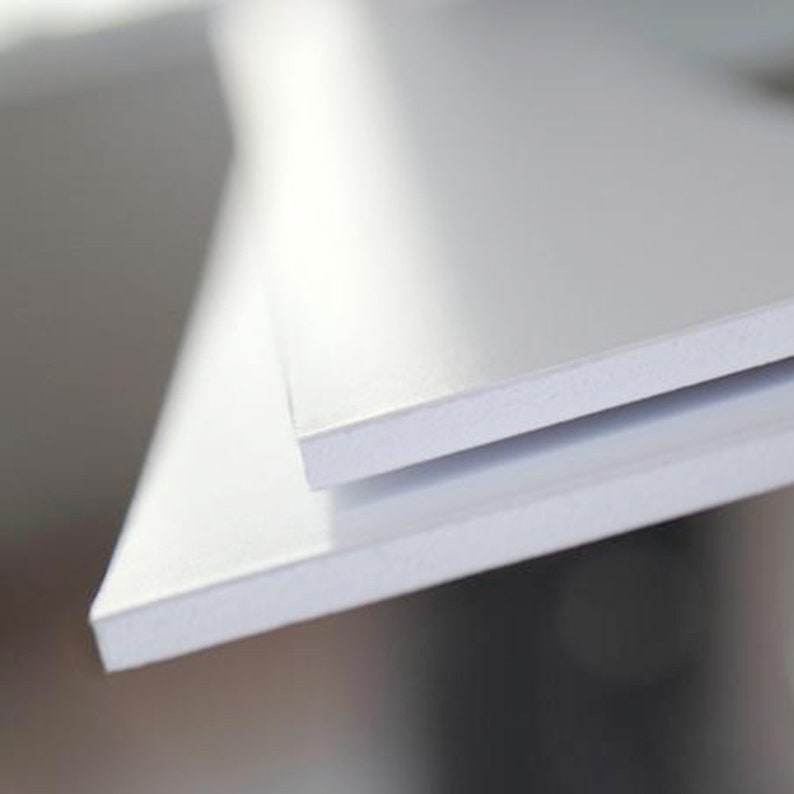 May include: Two white foam core boards stacked on top of each other. The top board is slightly angled to show the edge of the bottom board.