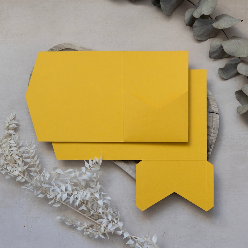 May include: A yellow paper pocket folder with a flap that folds over to create a pocket. The folder is on a wooden surface.