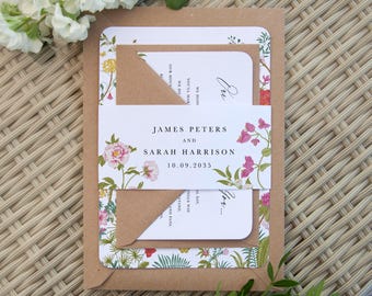 Puede incluir: Un juego de invitaciones de boda que incluye una tarjeta blanca con un borde floral colorido, un sobre de papel kraft marrón y una faja blanca impresa con los nombres James Peters y Sarah Harrison y la fecha 10.09.2035 en fuente serif negra.