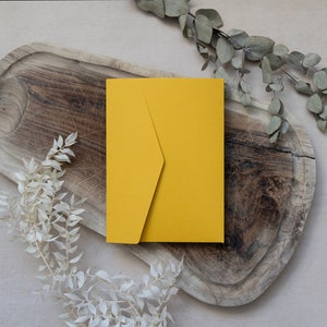 May include: A yellow envelope on a wooden surface with dried branches.