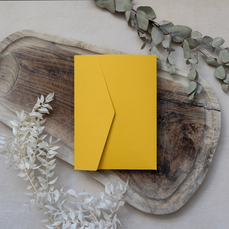 May include: A yellow envelope on a wooden surface with dried branches.