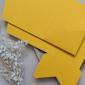 May include: A yellow paper box with a folded flap. The box is made of thick paper and has a smooth, matte finish.