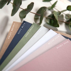 Pu&ograve; includere: Una collezione di campioni di carta in vari colori, tra cui marrone kraft, blu navy, verde salvia, grigio tortora, bianco, rosa tenue e rosa scuro. I campioni di carta sono disposti a ventaglio, con il colore pi&ugrave; scuro in basso e il colore pi&ugrave; chiaro in alto.