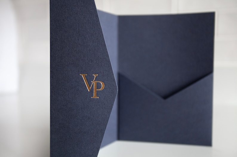 May include: Navy blue presentation folder with a gold foil "VP" monogram. The folder is open, revealing a pocket on the right side. The paper has a textured finish, and the background is white.