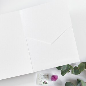 Pu&ograve; includere: Un biglietto bianco con una linguetta piegata. Il biglietto &egrave; vuoto e ha una superficie testurizzata. Un piccolo francobollo con un disegno floreale e il testo "Only Love is like a Red, Red Rose" &egrave; visibile nell'angolo in basso a destra.