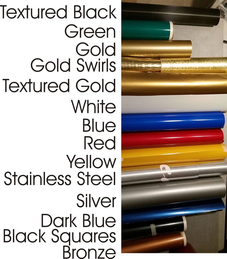 K&ouml;nnte beinhalten: Eine Auswahl an Rollen von Vinyl-Klebefolie in verschiedenen Farben und Texturen, darunter strukturiertes Schwarz, Gr&uuml;n, Gold, Gold mit Swirls, strukturiertes Gold, Wei&szlig;, Blau, Rot, Gelb, Edelstahl, Silber, Dunkelblau, schwarze Quadrate und Bronze.