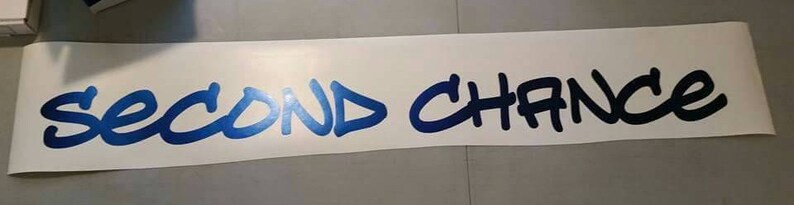 K&ouml;nnte beinhalten: Ein wei&szlig;er Vinyl-Aufkleber mit den Worten "Second Chance" in blauer und schwarzer Graffiti-Schrift.