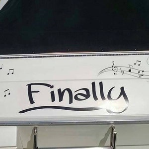 Könnte beinhalten: Weißes Boot mit einer schwarzen Vinyl-Abdeckung und dem Wort "Finally" in schwarzer Kursivschrift mit Noten darüber.