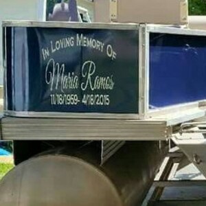 K&ouml;nnte beinhalten: Eine schwarz-wei&szlig;e Gedenktafel auf einem Pontonboot. Die Tafel tr&auml;gt die Aufschrift "In liebevoller Erinnerung an Maria Ramos 11/18/1959-4/18/2015".