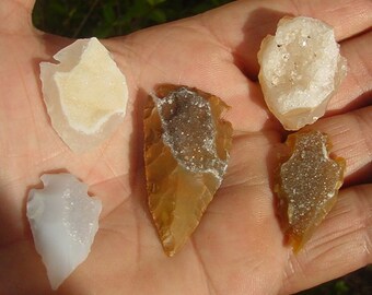 May include: Four arrowheads with a white, crystalline interior. The arrowheads are made of brown, gray, and white stone.
