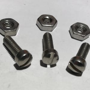 May include: Four silver screws with slotted heads and four silver hex nuts.