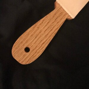 May include: A wooden strop with a leather strop attached to the top. The strop has a hole in the handle.
