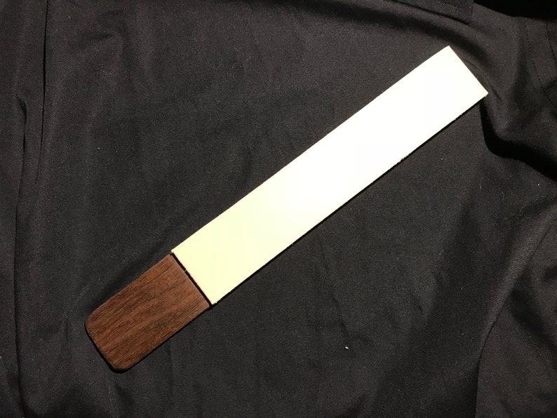 May include: A long, thin, white sanding block with a brown wooden handle.