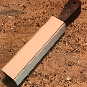 Peut inclure: Une strop en cuir brun clair avec une poign&eacute;e en bois brun fonc&eacute;. La strop est utilis&eacute;e pour aiguiser les rasoirs droits.