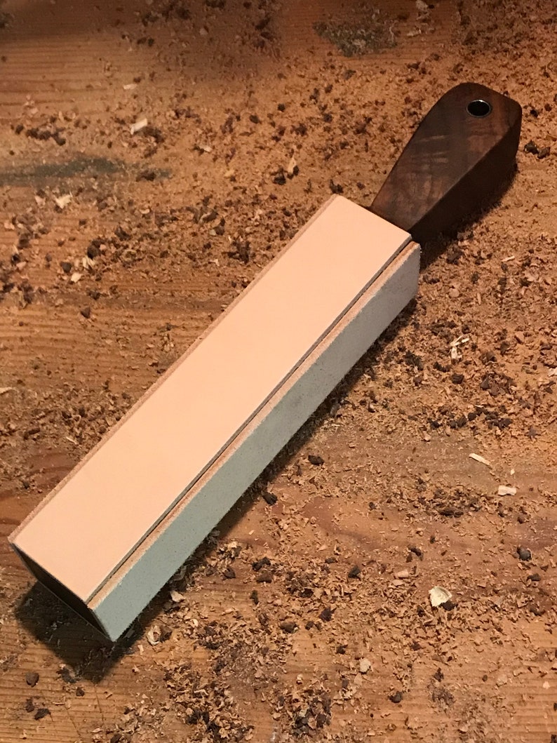 Peut inclure: Une strop en cuir brun clair avec une poign&eacute;e en bois brun fonc&eacute;. La strop est utilis&eacute;e pour aiguiser les rasoirs droits.