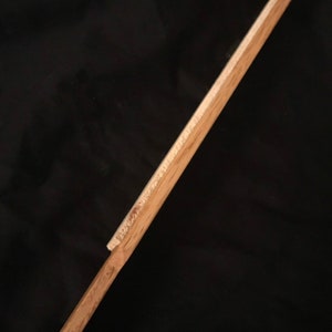 May include: A wooden dowel rod with a slightly rounded end. The rod is light brown in colour and has a smooth surface.