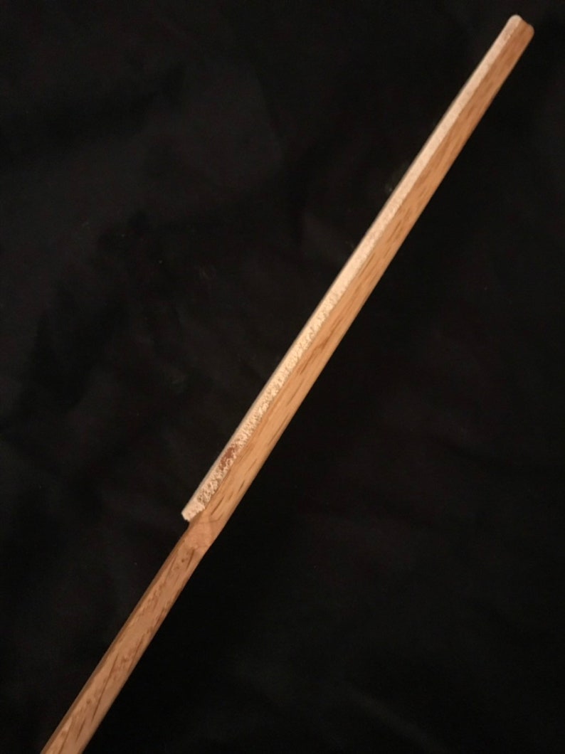 May include: A wooden dowel rod with a slightly rounded end. The rod is light brown in colour and has a smooth surface.