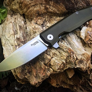 May include: A green folding knife with a silver blade. The blade is marked "Monosteel Italy M390".