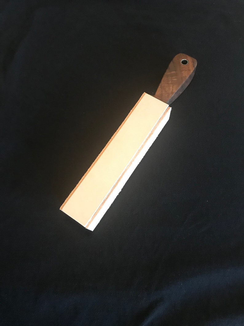 Peut inclure: Une strop en cuir blanc avec une poign&eacute;e en bois. La strop est utilis&eacute;e pour aiguiser les rasoirs droits.