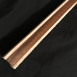 Puede incluir: Primer plano de una tabla de madera con tres capas de madera. La capa superior es de madera marr&oacute;n claro, la capa intermedia es de madera marr&oacute;n oscuro y la capa inferior es de madera marr&oacute;n claro.
