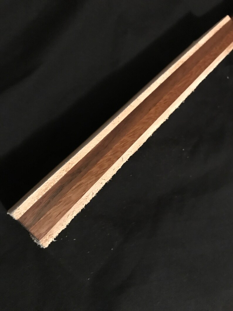 Puede incluir: Primer plano de una tabla de madera con tres capas de madera. La capa superior es de madera marr&oacute;n claro, la capa intermedia es de madera marr&oacute;n oscuro y la capa inferior es de madera marr&oacute;n claro.
