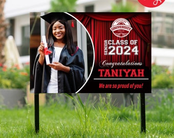 May include: A black and red graduation yard sign with a photo of a graduate in a cap and gown holding a diploma. The sign says "Class of 2024" and "Congratulations Taniyah".