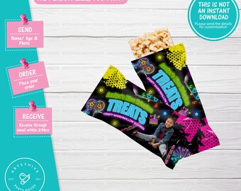 May include: Two black and pink treat bags with neon green and yellow accents. The bags have a design of a birthday cake, stars, and fireworks. The text on the bags reads "Janiya's Rice Krispies Treats, Crispy Marshmallow Squares".