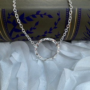 May include: A silver chain necklace with a textured, circular pendant.