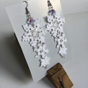Puede incluir: Pendientes blancos de copo de nieve, de ganchillo, con cuentas iridiscentes. Los pendientes presentan un diseño calado delicado, con múltiples formas de copo de nieve en cascada. Joyería hecha a mano.
