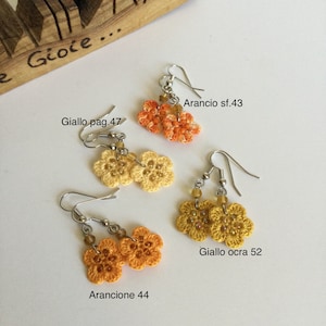 K&ouml;nnte beinhalten: Vier Paare geh&auml;kelter Blumenohrringe in Orange- und Gelbt&ouml;nen. Die Ohrringe sind mit italienischen Namen und Zahlen beschriftet, wie z. B. "Arancio sf.43" und "Giallo ocra 52".