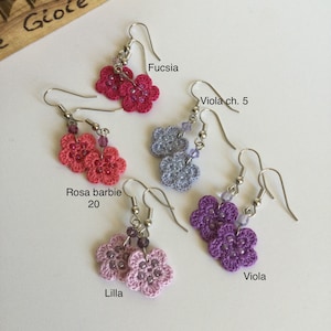K&ouml;nnte beinhalten: Sechs Paare geh&auml;kelter Blumenohrringe in verschiedenen Farben, darunter Fuchsia, Lila, Rosa und Grau. Jedes Paar besteht aus zwei kleinen geh&auml;kelten Blumen mit einem silbernen Haken.