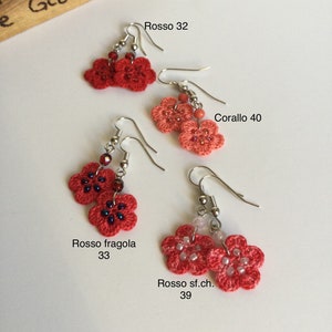 K&ouml;nnte beinhalten: Vier Paare geh&auml;kelter Blumenohrringe in verschiedenen Rott&ouml;nen und Korallenfarben. Die Ohrringe sind mit italienischen Namen und Zahlen beschriftet, wie z. B. "Rosso 32" und "Corallo 40".