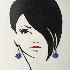 K&ouml;nnte beinhalten: Eine Schwarzwei&szlig;illustration einer Frau mit kurzen Haaren, die blaue bl&uuml;tenf&ouml;rmige Ohrringe tr&auml;gt.