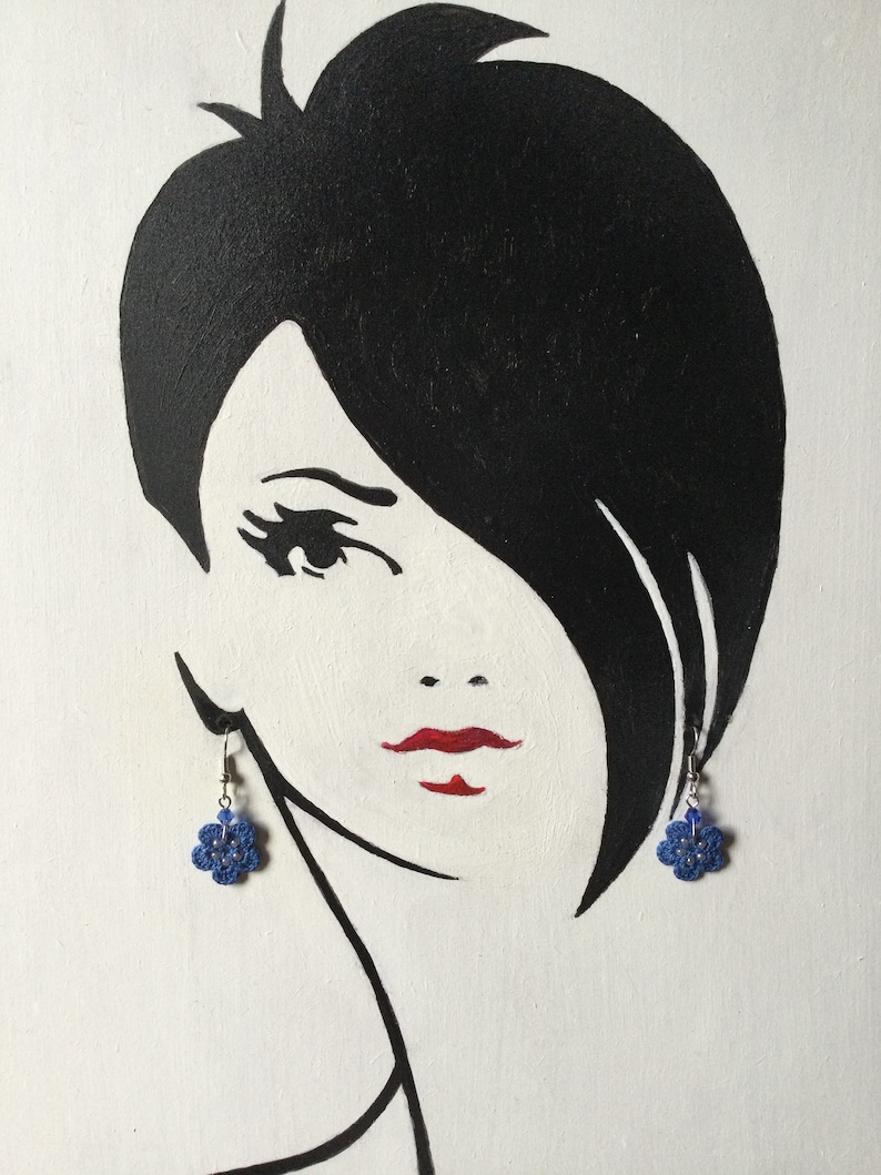 K&ouml;nnte beinhalten: Eine Schwarzwei&szlig;illustration einer Frau mit kurzen Haaren, die blaue bl&uuml;tenf&ouml;rmige Ohrringe tr&auml;gt.