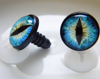 May include: Two blue and black plastic safety eyes with a white iris and black pupil. The eyes are on a white background.