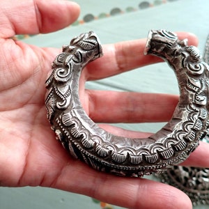 Può includere: Un braccialetto d'argento con intricati disegni floreali. Il braccialetto è aperto e ha una forma arrotondata. È fatto d'argento e ha una finitura lucida.