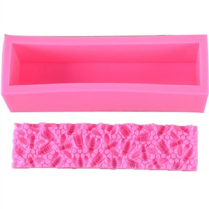 May include: A bright pink silicone soap mold with a rectangular shape and a detailed bee and honeycomb pattern. The mold is designed for creating handmade soaps or crafts, offering a decorative element.