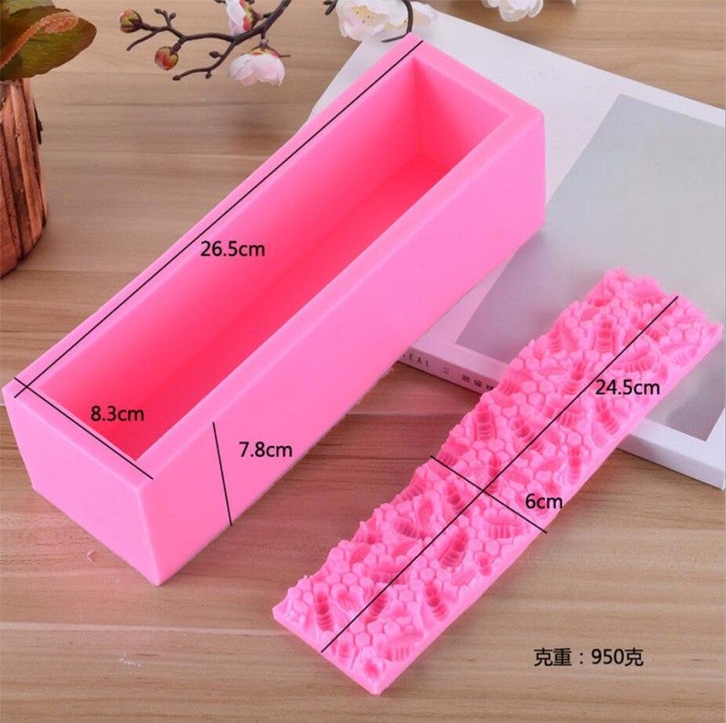 May include: A pink rectangular silicone soap mold, 10.4 inches long, 3.3 inches wide, and 3.1 inches deep, next to a pink silicone mold with a textured floral pattern, 9.6 inches long and 2.4 inches wide. The weight is 950 grams.