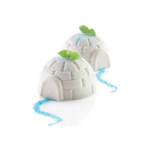 May include: Two white igloo-shaped cakes decorated with green mint leaves and blue sprinkles. The cakes are on a white surface.