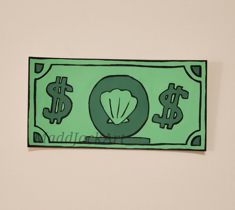 May include: A green paper bill with a seashell in the center and dollar signs on either side. The bill has a black outline and a green background.
