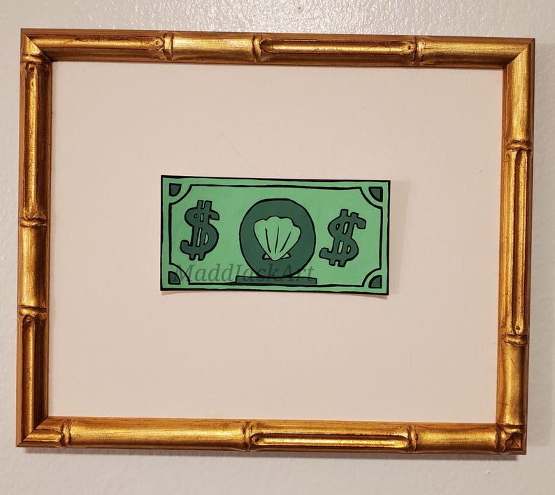 May include: A framed green paper bill with a seashell and dollar signs printed on it. The bill is titled "MaddJackArt".