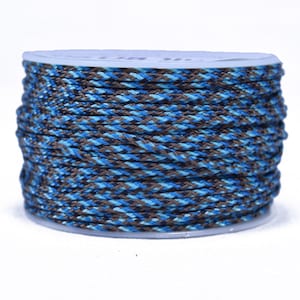 Puede incluir: Un carrete de cordón trenzado en tonos azules y marrones. El cordón está enrollado firmemente en un carrete de plástico transparente. El patrón trenzado crea una apariencia texturizada. Este cordón es adecuado para varios proyectos de artesanía.