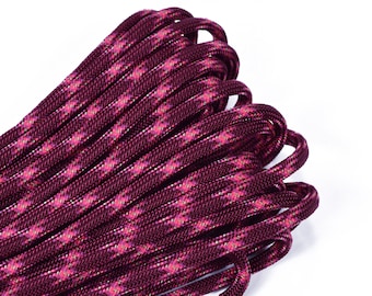 Puede incluir: Primer plano de una bobina de paracord marrón y rosa con un patrón de diamante. El paracord está enrollado apretado y tiene un acabado brillante.