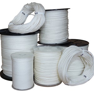 May include: Spools of white rope, varying in size, are stacked on top of each other. The rope is wound around black plastic spools.