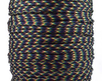 Könnte beinhalten: Eine Spule mit mehrfarbigem Paracord. Das Seil weist ein sich wiederholendes Muster aus Dunkelblau, Gelb, Grün und Orange auf. Die Spule ist zylindrisch und steht auf einer grauen Kartonbasis.