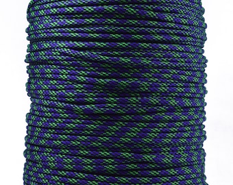 May include: A spool of green and purple paracord, a type of strong nylon rope, is wound around a brown cardboard spool.