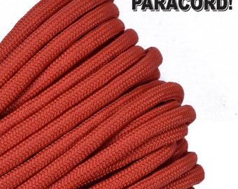 Puede incluir: Primer plano de un carrete de paracord rojo. El paracord está enrollado apretado y tiene una superficie texturizada.